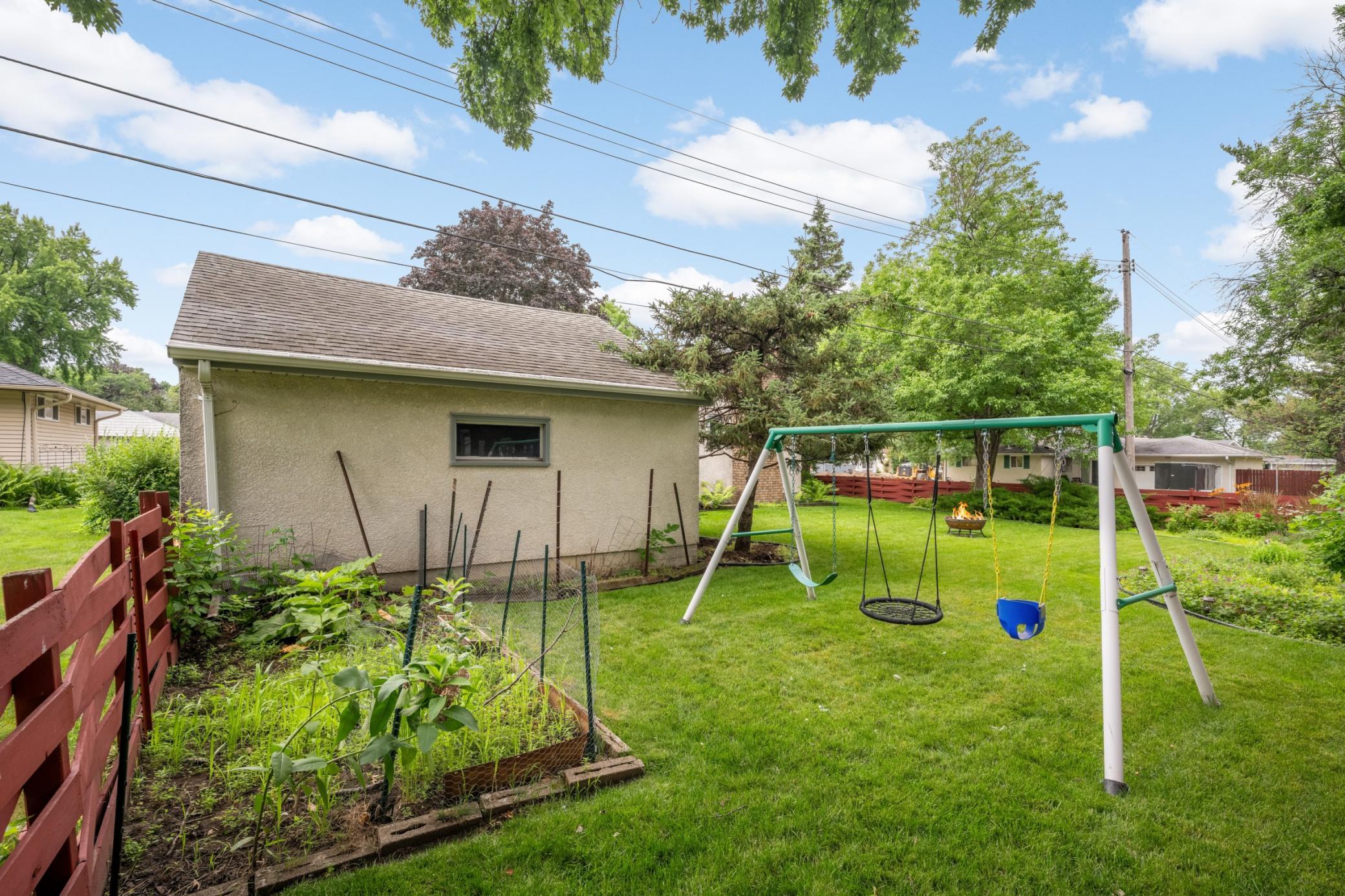 Play set and vegetable garden by the 2 car garage.