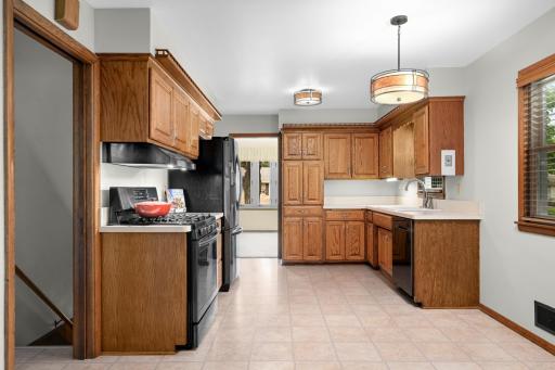 Kitchen with gas range, outside venting hood, oak cabinets, and room for a table.