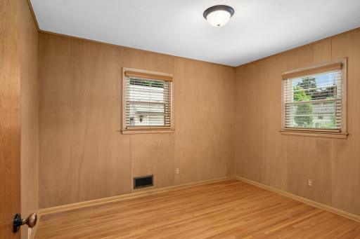 2nd main floor bedroom with hardwood floors and paneling.