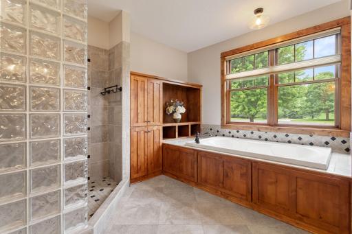 Primary suite bathroom with a large walk-in shower, jetted tub and built in cabinets and shelves