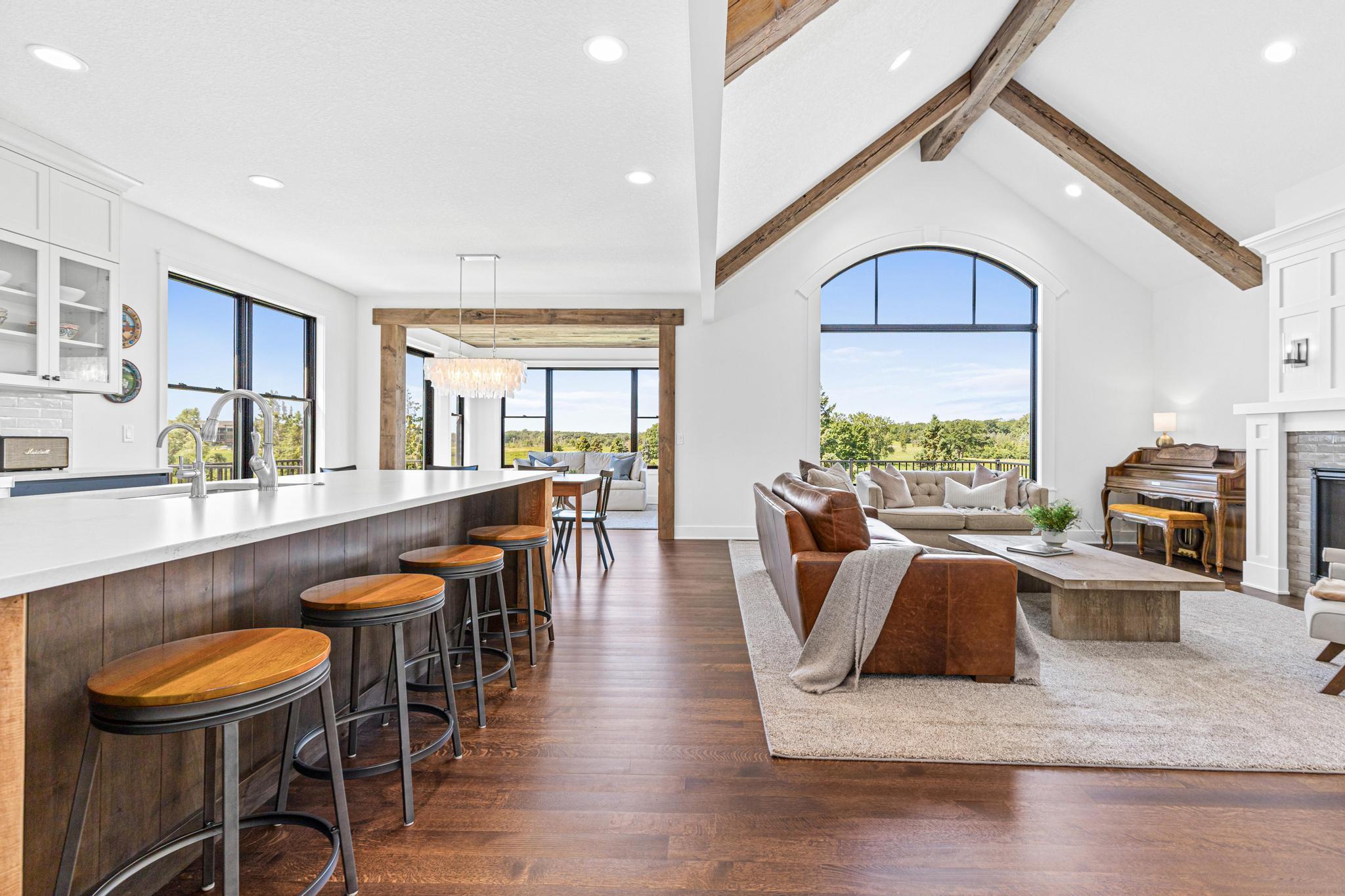 Soaring vaulted ceilings, exposed beams, and a dramatic wall of windows create a breathtaking great room filled with natural light. Open floor plan is perfect for entertaining small and large groups.
