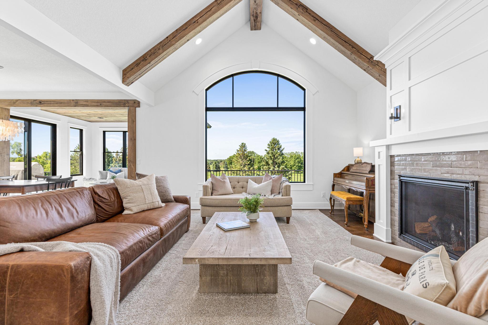 The breathtaking great room is anchored by soaring ceilings, reclaimed barn wood accents, and walls of windows overlooking nature.