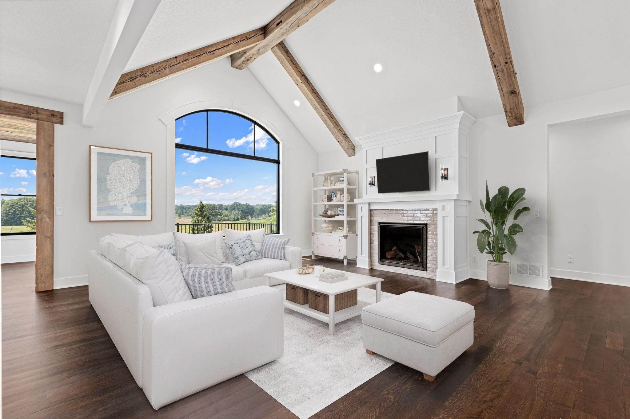 The breathtaking great room is anchored by soaring ceilings, reclaimed barn wood accents, and walls of windows overlooking nature. Visually staged.