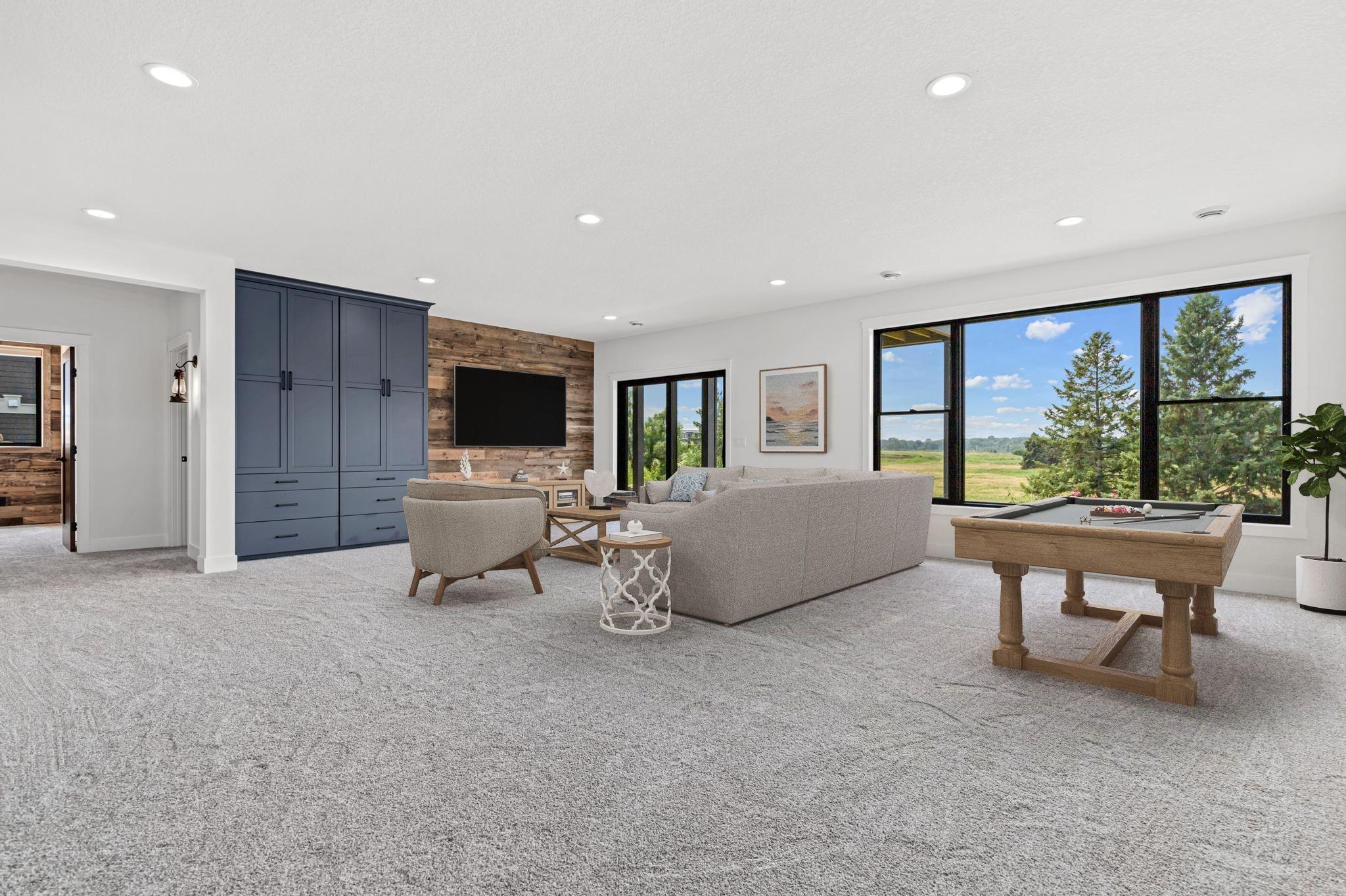 Downstairs, an entertainer's delight. Walk out lower level with large windows connecting interior spaces to the outdoors. The perfect place to watch the big game or your favorite movie. Virtually staged.