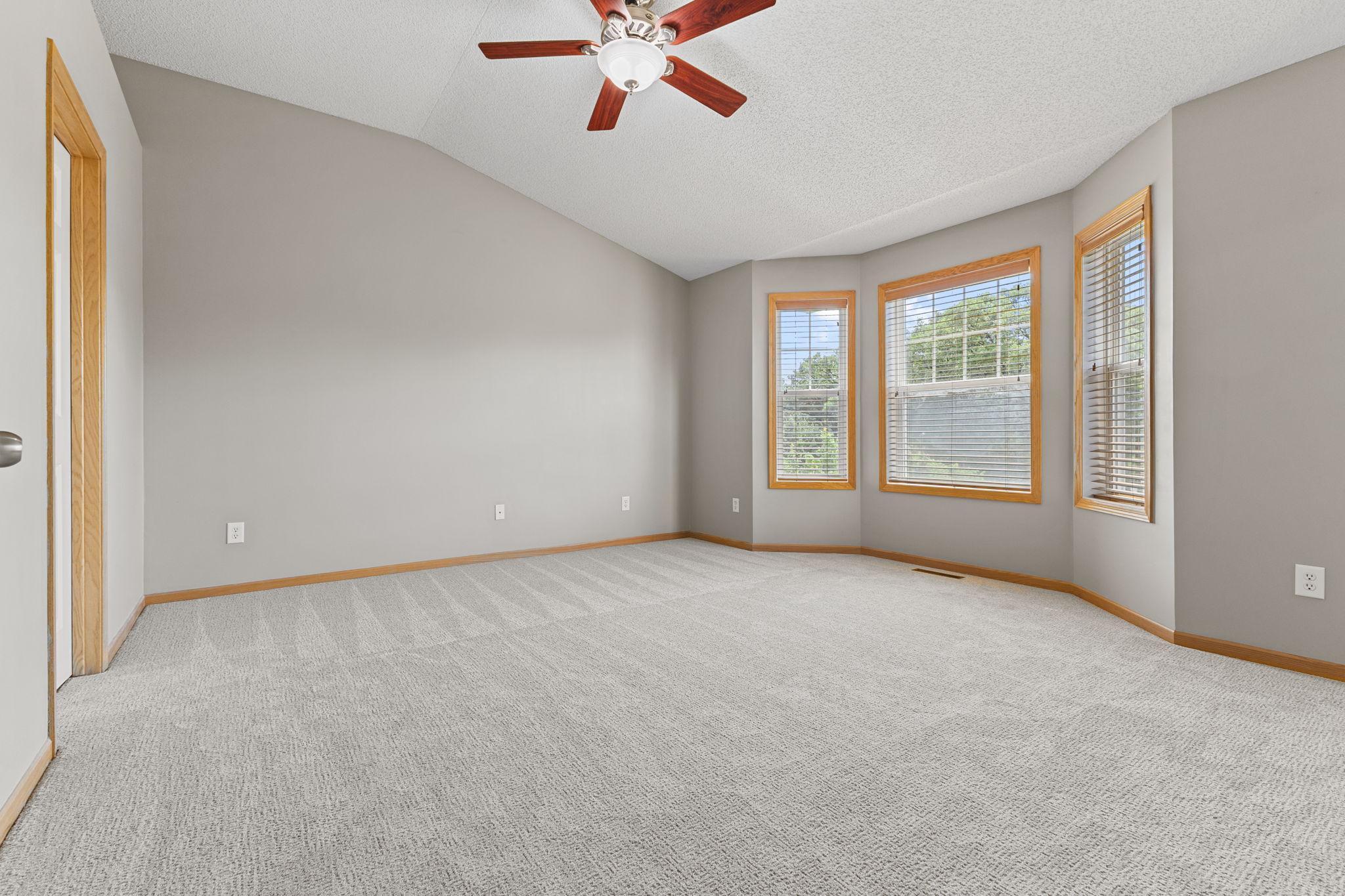 Primary bedroom with vaulted ceilings and bay window
