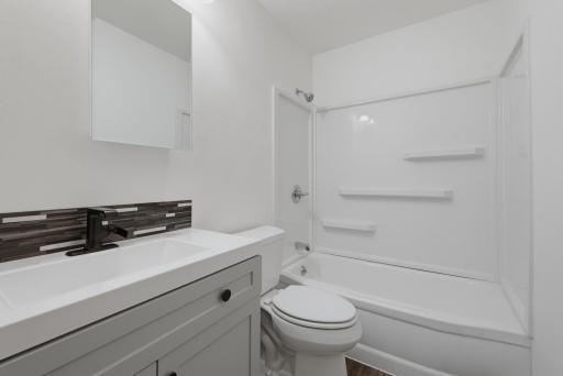 The full bathroom features durable vinyl plank floors.