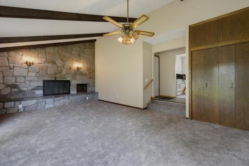 Step into the main floor family room. Vaulted ceilings with wood beams, a woodburning fireplace with a stone surround, and new carpet are featured.