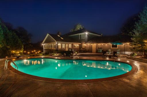 A nighttime view of the pool and surrounding patio area.