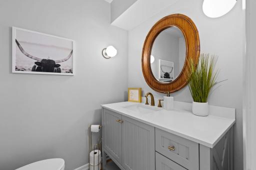 Just off the entry, a conveniently located powder room that showcases contemporary LED lighting, a newly installed toilet, and a stylish updated vanity.