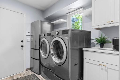 Completing the main level is a well-appointed laundry featuring an updated half bath, high-efficiency LG front-loading washer and dryer, utility sink, ample cabinetry, and a slim-profile GE refrigerator and freezer with ice maker.