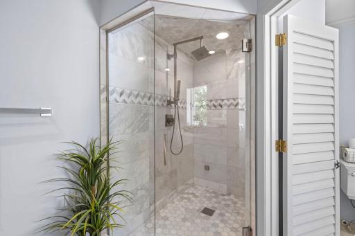 Comfortable heated floors and a stunning Carrara marble walk-in steam shower with both rainfall and handheld showerheads create a spa-inspired retreat for everyday relaxation.