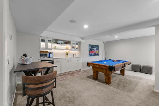 A well-appointed wet bar enhances the recreation space with a beverage refrigerator, LED lighting, ample counter space, and cabinetry.