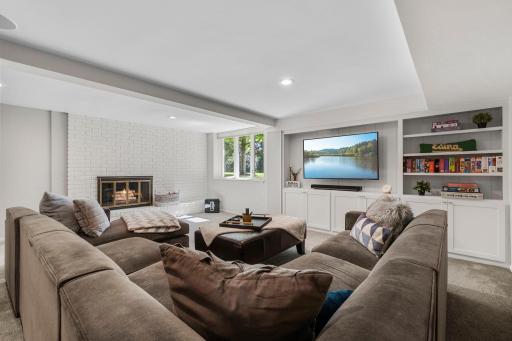 The family room features carpeting, a wood-burning fireplace framed by custom built-in shelving, and a recessed TV space for a clean, functional layout.