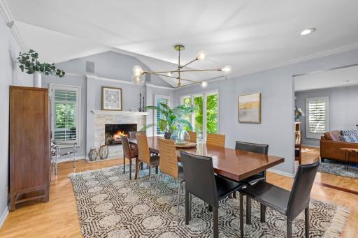 The impressive formal dining room serves as a standout gathering space, highlighted by vaulted ceilings, distinctive gold modern lighting, and a cozy wood-burning fireplace.
