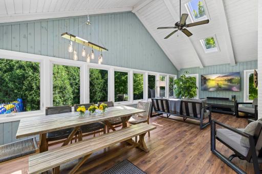 The four-season porch provides year-round enjoyment with soaring vaulted ceilings, skylights, luxury plank flooring, a mini-split heating and cooling system (2024), and new double-pane expanded-view windows that flood the space with natural light.