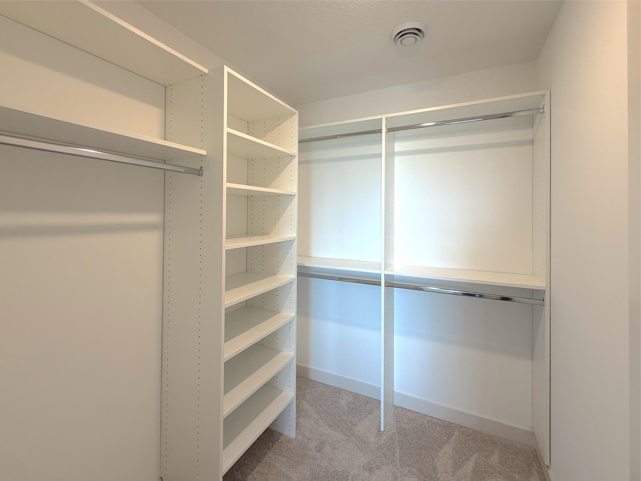 The spacious walk-in closet is thoughtfully designed with built-in shelving and multiple hanging areas, making it easy to keep wardrobes organized.