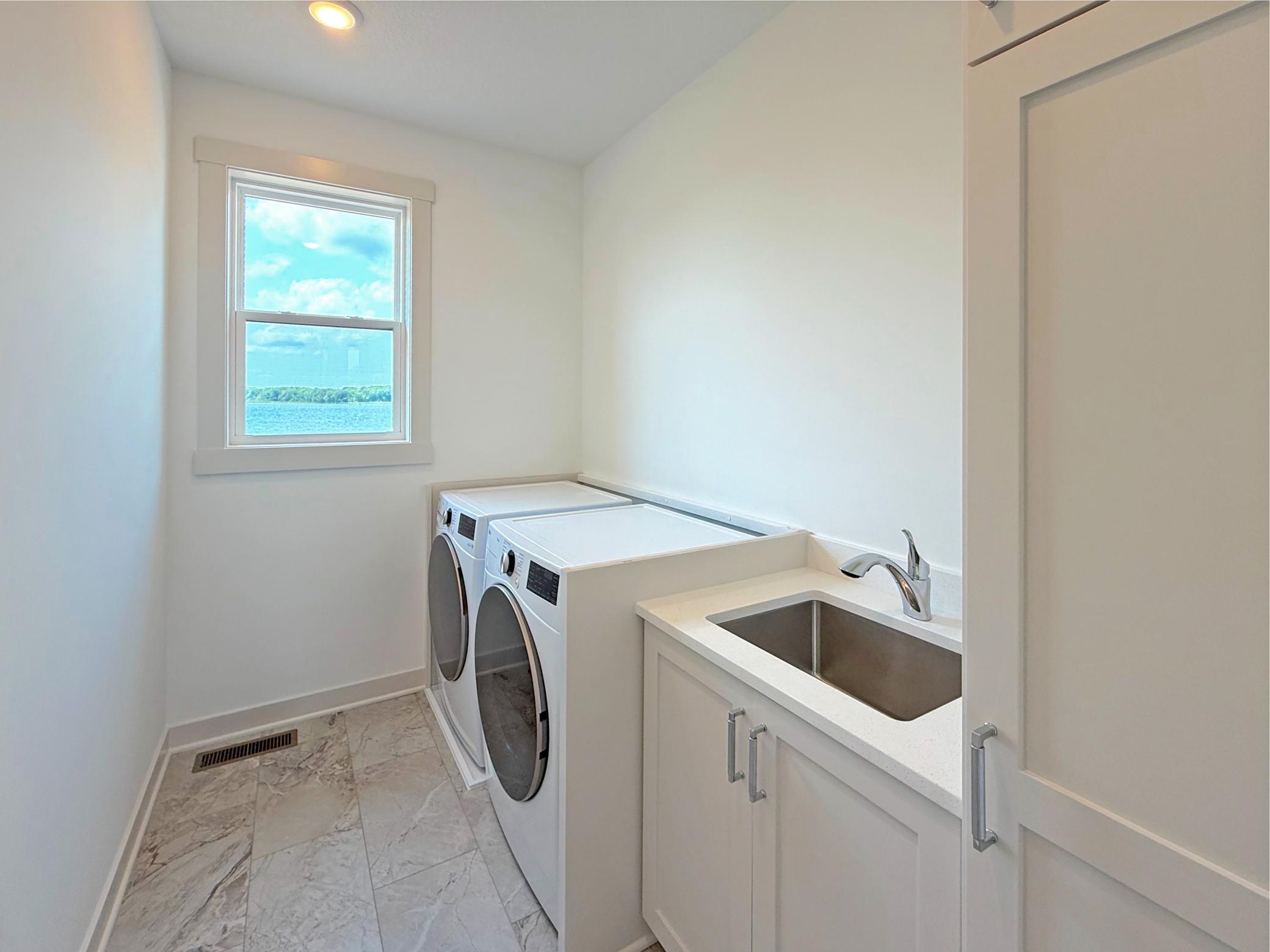 The thoughtfully designed main-level laundry room features a utility sink, fantastic flooring, custom cabinetry, and beautiful lake views, making everyday chores a little more enjoyable.