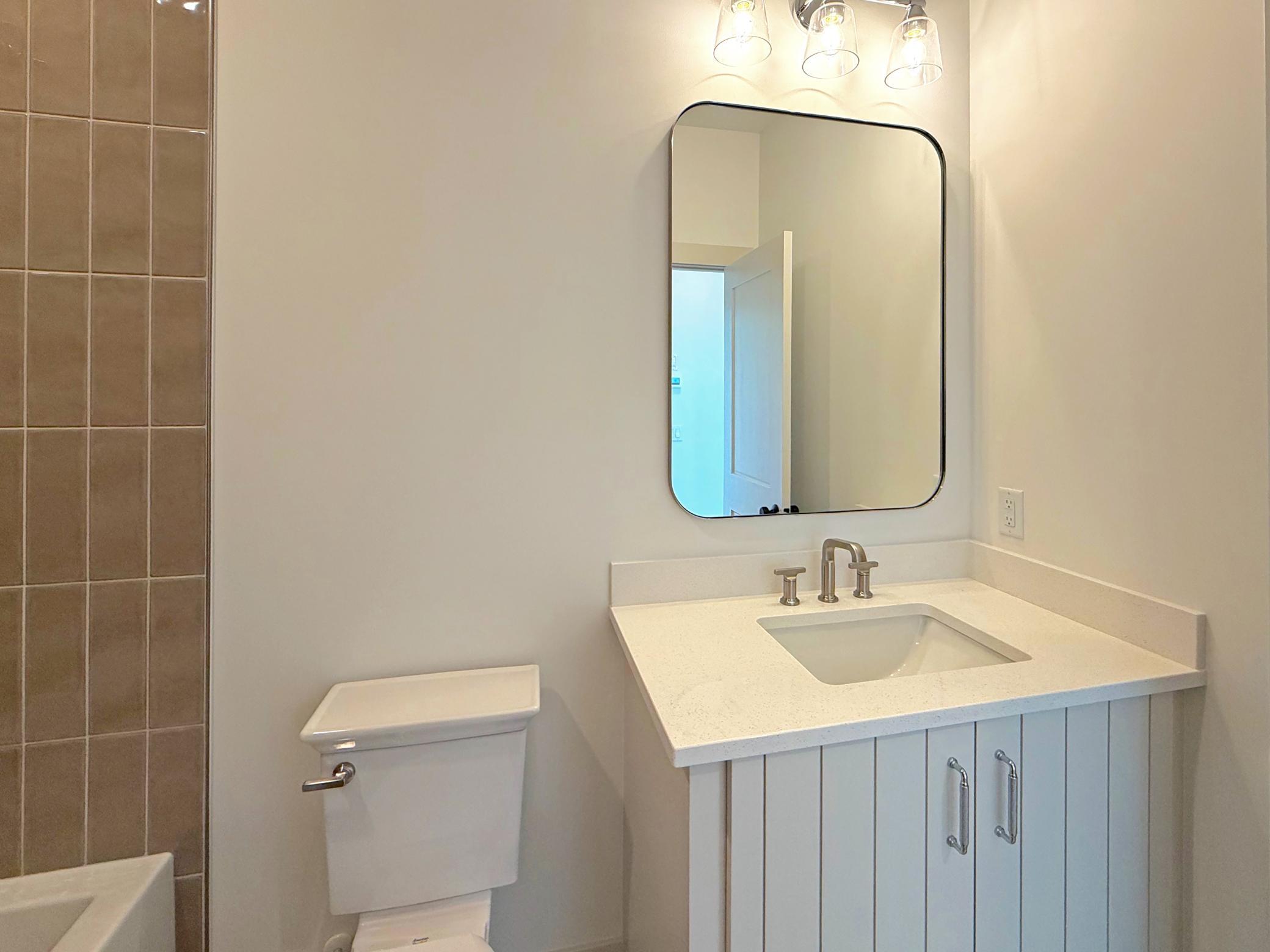 The main-level full bathroom features a quartz-topped vanity, modern fixtures, and clean, timeless finishes designed to complement the home's upscale style.