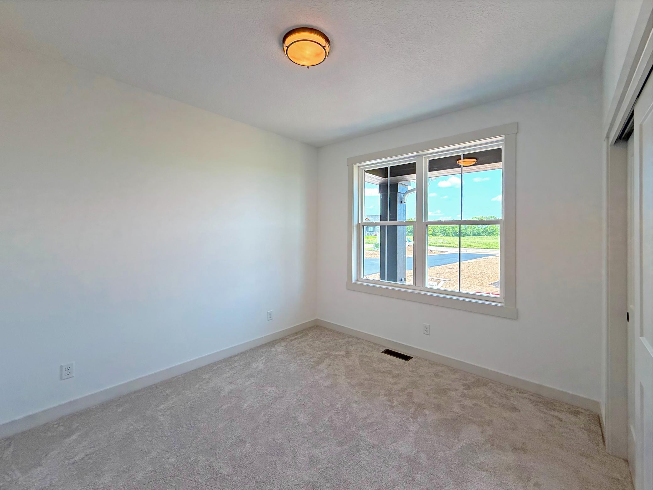 The second main-level bedroom offers a bright and comfortable retreat with a large window, generous closet space, and versatile use as a guest room or home office.