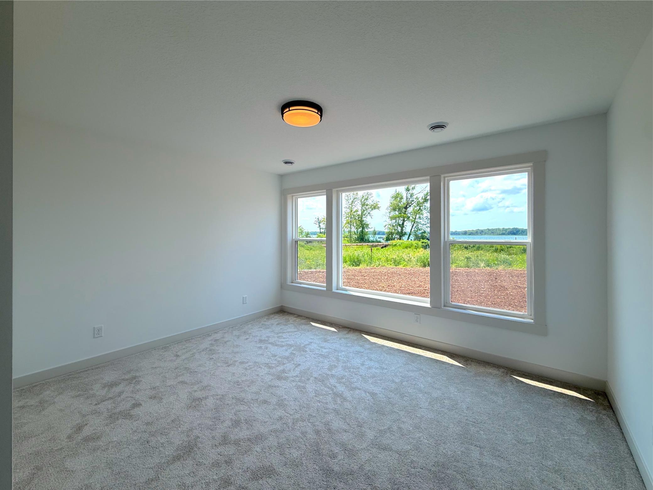 The fourth bedroom offers a peaceful retreat with oversized windows that fill the room with natural light while capturing beautiful views of the lake and surrounding landscape.