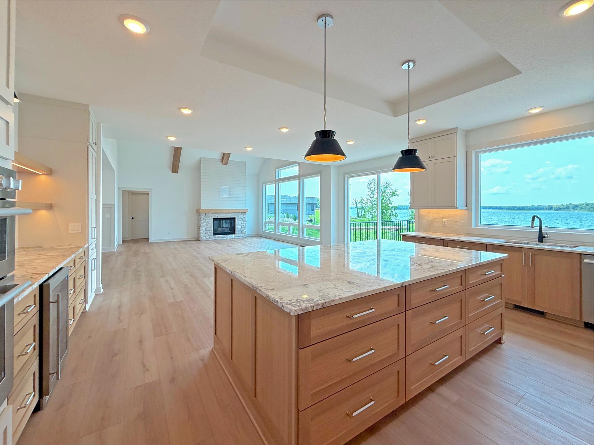 Expansive windows fill the kitchen with natural light while showcasing beautiful lake views. The open-concept design flows effortlessly into the dining area and great room.