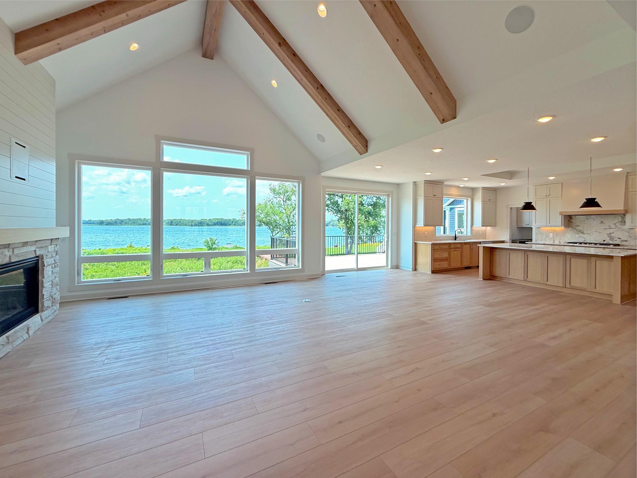 The breathtaking living room is designed to impress with soaring vaulted ceilings accented by exposed wood beams and a stunning floor-to-ceiling stone fireplace.