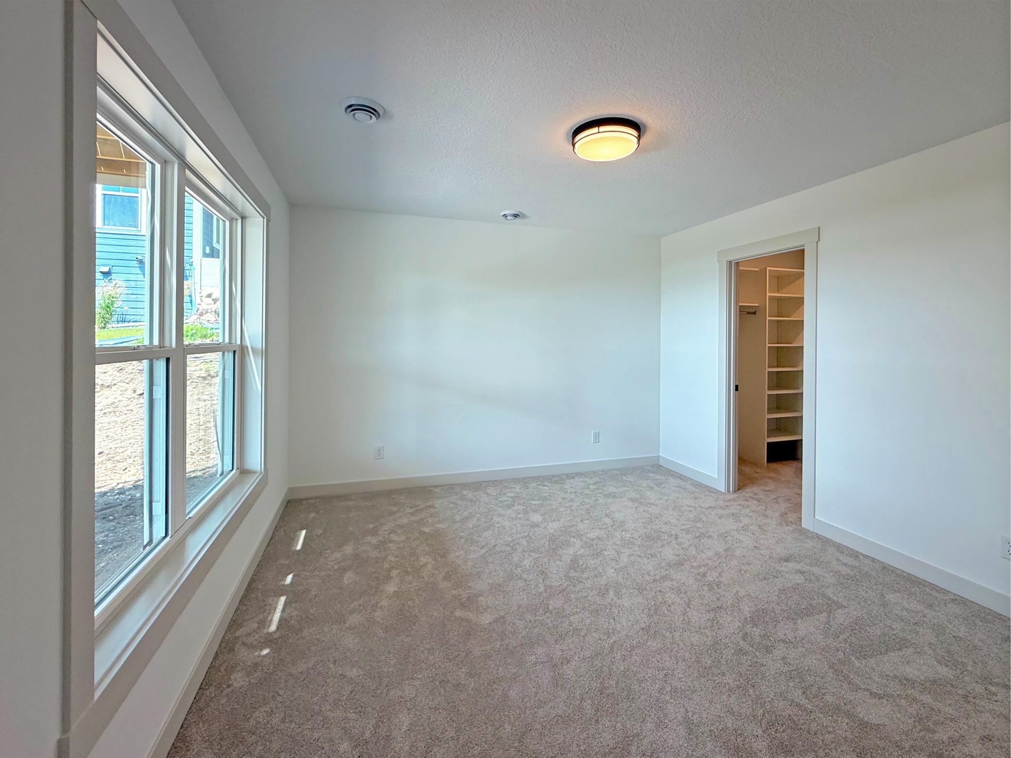 This bright and inviting lower-level bedroom features a large window that fills the space with natural light, creating a comfortable retreat for family or overnight guests.