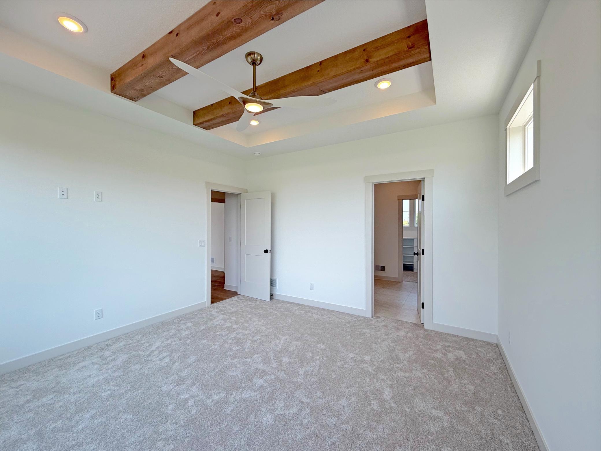 A dramatic box-vault ceiling accented with rustic wood beams creates warmth and architectural character, while soft natural light enhances the suite's inviting atmosphere.