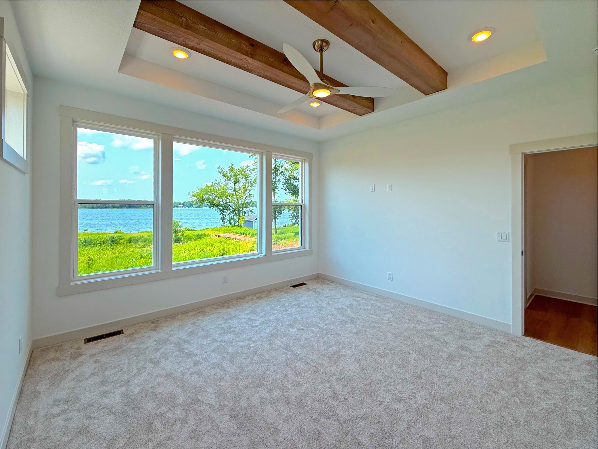 Wake up to breathtaking lake views from the comfort of your primary suite, where oversized windows bring the outdoors in and create a serene setting for relaxation.