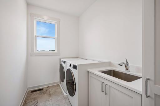 The thoughtfully designed main-level laundry room features a utility sink, fantastic flooring, custom cabinetry, and beautiful lake views, making everyday chores a little more enjoyable.