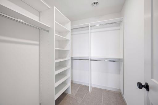 The spacious walk-in closet is thoughtfully designed with built-in shelving and multiple hanging areas, making it easy to keep wardrobes organized.