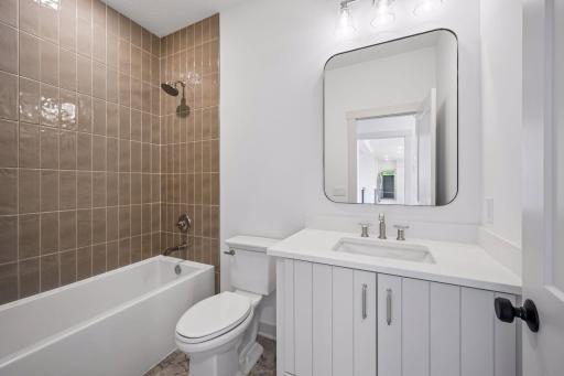 The main-level full bathroom features a quartz-topped vanity, modern fixtures, and clean, timeless finishes designed to complement the home's upscale style.