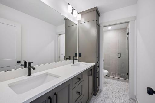 Contemporary finishes define this spacious full bathroom, complete with a custom double vanity, designer fixtures, and a sleek tiled walk-in shower that complements the home's upscale style.