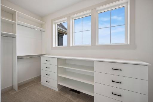 Designed with organization in mind, the spacious walk-in closet features a built-in wardrobe system with generous drawers, shelving, and hanging space, all illuminated by natural light.