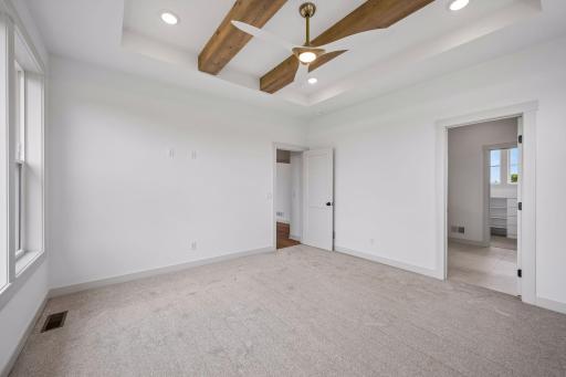 A dramatic box-vault ceiling accented with rustic wood beams creates warmth and architectural character, while soft natural light enhances the suite's inviting atmosphere.