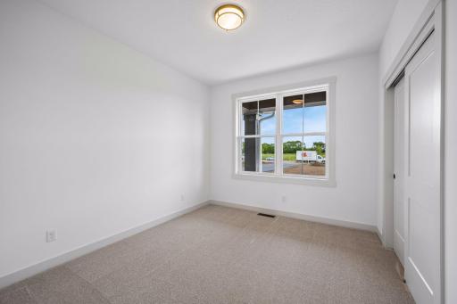 The second main-level bedroom offers a bright and comfortable retreat with a large window, generous closet space, and versatile use as a guest room or home office.
