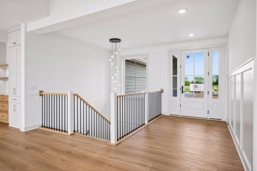 The open staircase makes a striking architectural statement with sleek iron balusters, warm wood handrails, and a designer cascading pendant that elegantly connects the home's two levels.