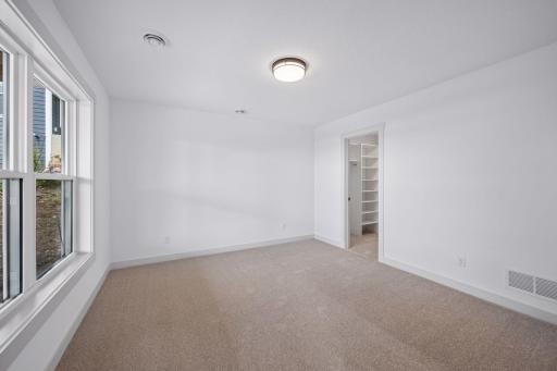 This bright and inviting lower-level bedroom features a large window that fills the space with natural light, creating a comfortable retreat for family or overnight guests.
