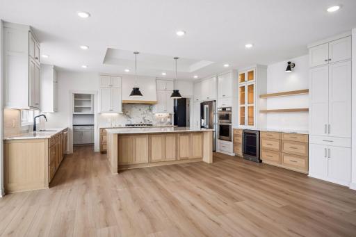 Thoughtfully designed with custom cabinetry, illuminated glass display cabinets, a built-in beverage refrigerator, floating wood shelves, this kitchen blends elegance with everyday convenience.