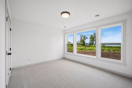 The fourth bedroom offers a peaceful retreat with oversized windows that fill the room with natural light while capturing beautiful views of the lake and surrounding landscape.