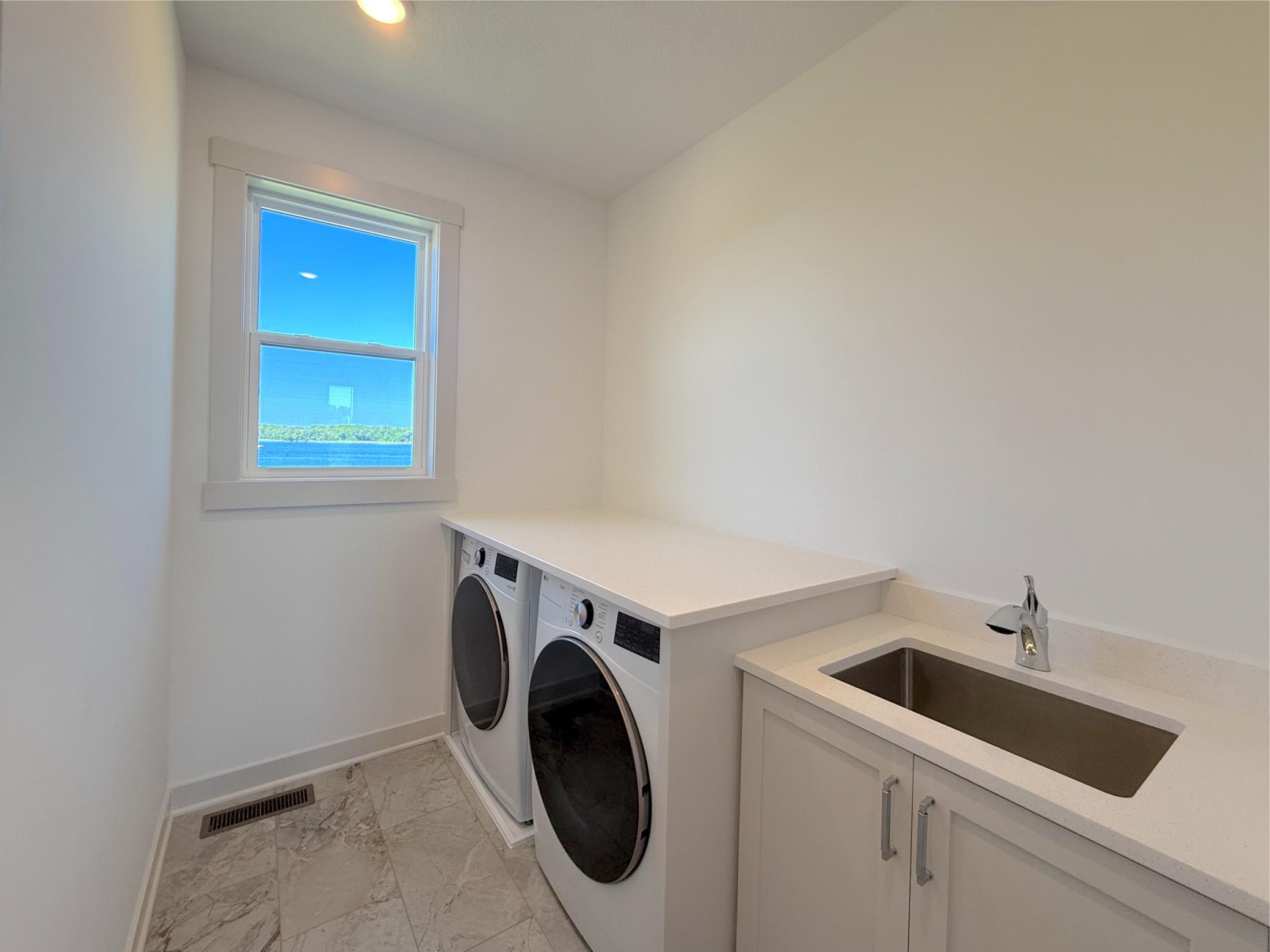 The thoughtfully designed main-level laundry room features a utility sink, fantastic flooring, custom cabinetry, and beautiful lake views, making everyday chores a little more enjoyable.