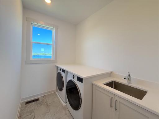 The thoughtfully designed main-level laundry room features a utility sink, fantastic flooring, custom cabinetry, and beautiful lake views, making everyday chores a little more enjoyable.