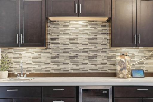 Wet bar features tile backsplash, mini refrigerator, sink and space to add a microwave.