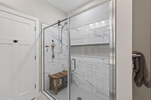 Primary bath features a tiled walk-in shower with built-in niche and glass enclosure.