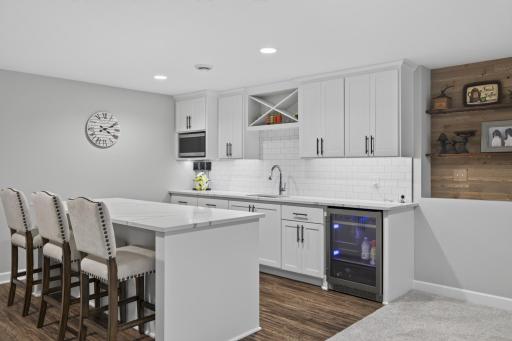 Hospitality bar with island seating, sink, beverage refrigerator, and microwave.