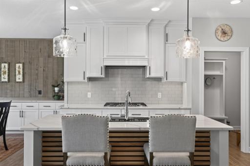 Quartz island with seating and access to walk-in pantry through the mudroom to the right.