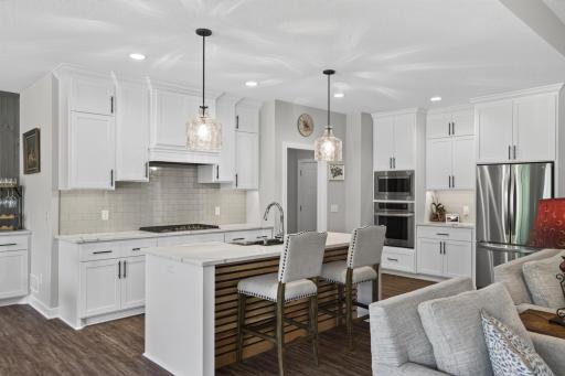 Quartz countertops, ceiling-height cabinetry, and gas cooktop.