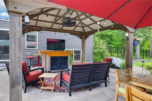 One of three covered outdoor gathering spaces, features a ceiling fan and paver patio.