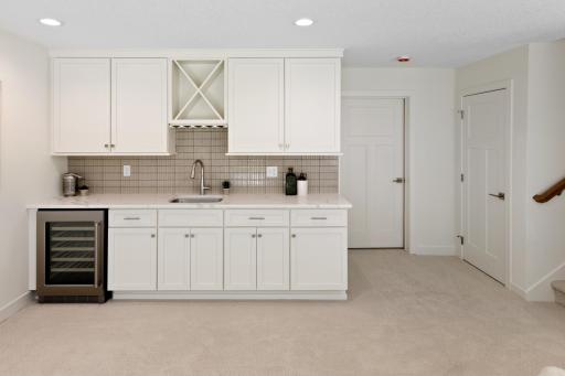 Lower level wet bar with beverage refrigerator is the perfect space to set out food and drink when entertaining!
