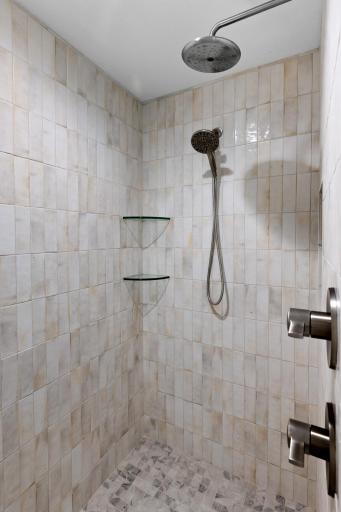 The stylish walk-in shower has amazing tilework and rain shower head with hand sprayer.